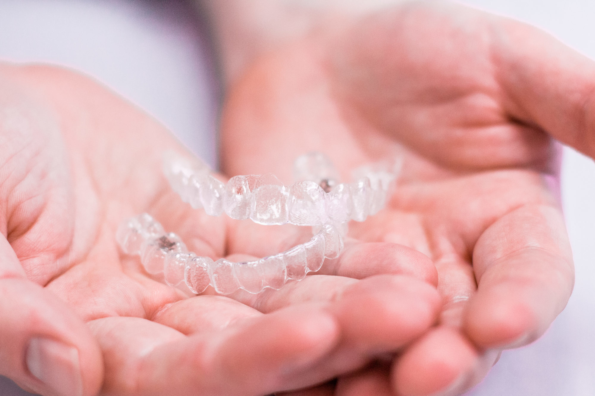 Hands holding Invisalign aligners